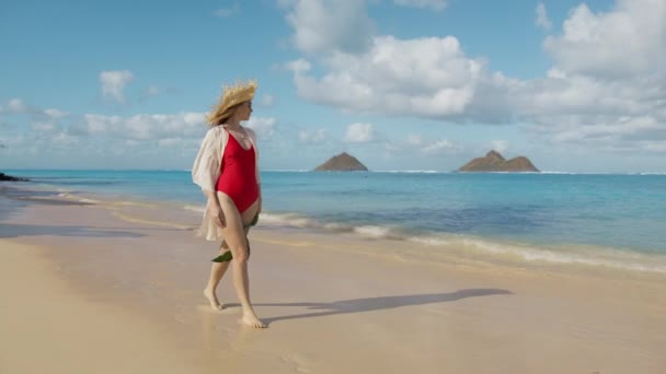 在太平洋完美的夏威夷岛度暑假的时候 快乐而又轻松的人们 30多岁的女人 身穿红色泳衣 头戴布荷草帽 身穿比基尼泳衣的年轻女子与Pareo Ohu 4K合影 — 图库视频影像