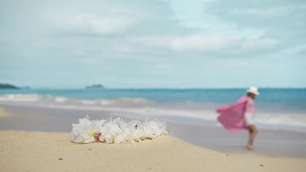 幸せなのんきな女性は ピンクのドレスを飛んで幸せを感じる海のビーチを楽しんで 熱帯の白い蘭の花のレイネックレスを閉じます エレガントな衣装で無料の喜びの女の子リラックス 完璧なハワイの白い砂 — ストック動画
