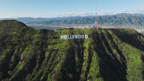 空中ヘリコプタービュー ロサンゼルス市カリフォルニア州2023年3月 ハリウッドの素晴らしい景色バーバンクと高い山の頂上を背景に雲に覆われた美しい緑の丘にサイン — ストック動画