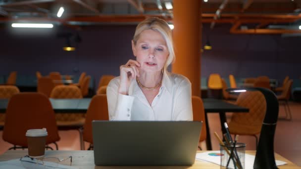 在现代办公室里 一个微笑的女商人在网上的视频会议上说话 在室内笔记本电脑上进行视频通话的成熟员工 阁楼同事工作场所的女性专业人员解释项目 — 图库视频影像
