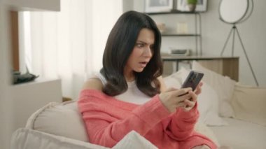 Kanepede oturan endişeli kadın elinde akıllı telefonuyla e-banka uygulaması kullanarak güvensiz online ödeme yapmaya çalışıyor. Para yüzünden sorunlarla yüzleşen bir kız. Banka dolandırıcılığı sorunu, başarısız işlem kavramı