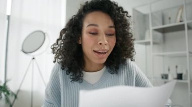 Web kamerası görüntüsü genç iş kadını ofis masasındaki şirket evraklarını kontrol ediyor. Belgeleri okuyan, mali belgeleri analiz eden, rapor hazırlayan etkileyici kadın girişimci.