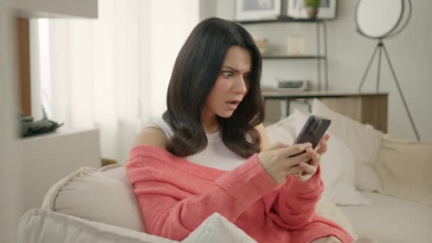 スマートフォンを持ってソファに座っている心配の女性は 電子銀行アプリを使用して安全でないオンライン決済をしようとしています 問題に直面している女の子はお金がない 銀行詐欺の問題 失敗した取引の概念 — ストック動画