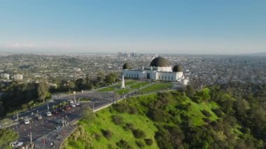 Griffith Gözlemevi Kubbeleri, güneşli bir yaz gününde, Hollywood Dağı 'ndaki yeşil parkta mavi gökyüzünün altında nefes kesici bir manzara. Çim gözetleme güvertesi antenine giriş. Los Angeles şehri Kaliforniya ABD Mart 2023