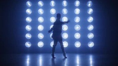 Profesyonel RNB dansçısının silueti parlak renkli ışıklar altında kalçalarını oynatıyor. Gece kulübünde son moda kıyafetli şık bir dansçı konser veriyor. Gece hayatı, parti konsepti çekimi