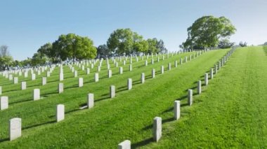 Huzurlu cenaze konsepti. Los Angeles Ulusal Mezarlığı, Kaliforniya ABD. İnsansız hava aracı, yaz günü düz sıra beyaz mezar plakalarıyla yeşil arazi üzerinde uçuyor. Silahlı Kuvvetler Ulusal Mezarlığı