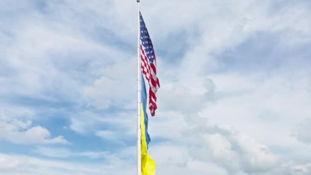 由美国国旗和乌克兰国旗组成的具有戏剧性的无人驾驶航空器以慢动作一起摇曳着 巨大的美国国旗和乌克兰国旗在蓝天上飘扬 白云缭绕 对俄国战争的象征性支持 — 图库视频影像