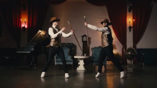 ミュージックビデオ ナイトショー またはイベント4K ダンディスタイルの衣装を着た2人の男は レトロな劇場のステージで同期的に踊ります ジャズファンクスタイルで演奏する古典的な男性ダンサー 手で古典的な杖で踊る — ストック動画