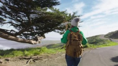 Kırmızı Kamera sırt çantalı turist kadını takip ediyor. Manzaralı yeşil tepeli güzel bir manzara Rey 'lerin okyanus sahilleri güneşli bahar doğa macerası, California. Sinema yavaş çekim ABD turizmi