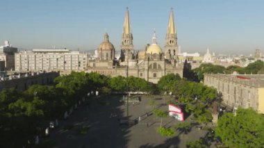 Guadalajara Katedrali 'nin önü Meksika. Gökyüzü karenin üzerinde, Gotik kuleleri olan güzel mavi gökyüzü. Guadalajara 'daki yeşil plaza parkı. İHA, Liberacion 4K plazasında yavaş uçuyor.