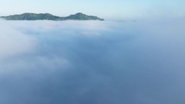 İnanılmaz doğa manzarası, gökyüzünde 4K drone. Yoğun sisli bulutların üzerinde dron yükseliyor. Güneş doğarken pembe gökyüzü ile mavi bulutlardan oluşan güzel bir okyanus. Ufuk çizgisine kadar sonsuz bulut denizinin üzerinde hızla uçan drone.