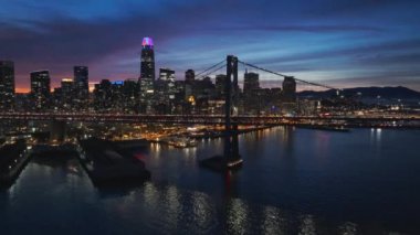 Alacakaranlık körfez köprüsünden San Francisco şehir merkezine doğru uçuyor. San Francisco City 'nin gökdelenleri ile geceleyin Kaliforniya' nın limanında gökyüzü manzarası oluşturuluyor. Geceleri güzel şehir manzarası