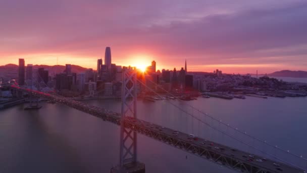 金融区大楼和湾桥上方色彩艳丽的落日天空 旧金山市市中心 在史诗般的夕阳西下紫色的天空4K空中 旧金山上空迷人的粉色金色落日云彩 — 图库视频影像