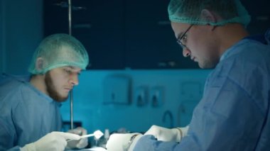 Gaziler veteriner kliniğindeki masada evcil hayvan için ameliyat yapıyorlar. Veteriner ameliyatı ağır çekimde. İki erkek cerrah. Veterinerlik kliniğinde başarılı bir ameliyat sırasında odaklanmış veteriner ve asistan