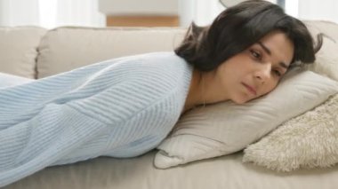Depresyon kavramı. Uykuda yatan yorgun latin kız. Enerji motivasyonunu kaybetmiş. Yorgun, tembel, genç, melez bir kadın kanepeye düşüyor. Duygusuz, sıkkın kadın evde tek başına uyuyor.