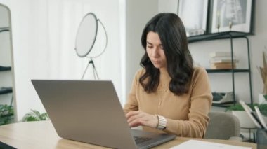 Latin iş kadını stres hissediyor ve ara vermeye ihtiyacı var. Ellerini başının arkasına koyuyor. Endişeli genç İspanyol iş kadını bilgisayar işini uzaktan çalışma masasında otururken bitirmiş.