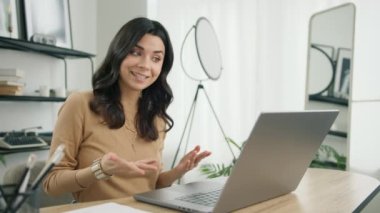 Gülümseyen İspanyol kız öğrenci çevrimiçi öğretmenle e-posta öğreniyor, öğretmenle konferans görüşmesi yapıyor. Video sohbet dili öğrenen bir kız, ofis masasında oturuyor, dizüstü bilgisayarı yavaş çekimde seyrediyor.