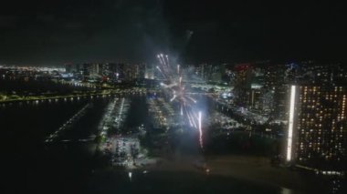 İnsanlar Hawaii tatili sırasında Oahu adasında havai fişeklerle kutlama yapıyorlar. Şehir siluetinde parlak havai fişek patlaması. Havai fişek gösterisi Waikiki plajı. Honolulu 'da Yeni Yıl Arifesi