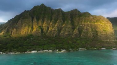 Altın saatinde muhteşem orman dağları olan yeşil tropikal ada. Oahu Adası 'ndaki destansı Kualoa Çiftliği sıradağları manzarasında gün doğumu ışığı parlıyor. İnsansız hava aracı cenneti Hawaii doğa yolculuğu