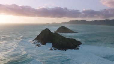 Na Mokulua Adaları 'na güneş doğarken, Kailua Oahu Adası, Hawaii Birleşik Devletleri' nde manzara dalgaları çarpıyor. Pasifik Okyanusu 'ndaki küçük ada silueti. Hawaii tatili. Turizm arka planı 4K destansı gün doğumu