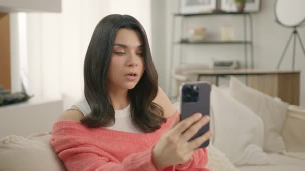 Sorprendido Joven Morena Hablando Videollamada Usando Smartphone Sala Estar Casa — Vídeos de Stock