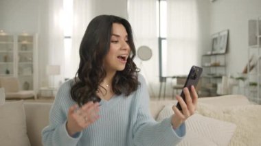 Kocasıyla, erkek arkadaşıyla ya da akrabalarıyla kanepesinde selfie ya da video görüşmesi yapan otantik, mutlu, zarif bir kadın. Modern teknoloji kavramı, aile yavaş çekim 4K video ile kablosuz bağlantı