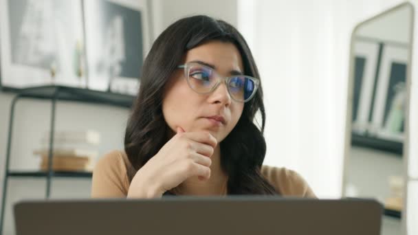关心戴眼镜的拉丁女人在笔记本电脑上工作 把目光移开 想着如何在总部解决问题 密切关注认真的女性寻找灵感 做出缺乏创意的决定4K — 图库视频影像