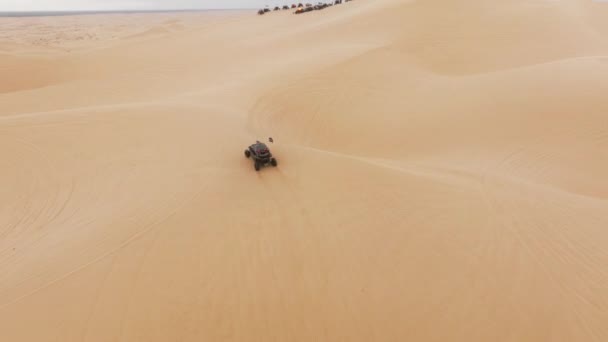 砂の砂丘に乗ってAtvバギースポーツ車の空中ビュー 週末の日のための極端なスポーツ屋外趣味活動 男性のためのスポーツレクリエーションの概念 砂丘で競争する四輪駆動車のグループ — ストック動画