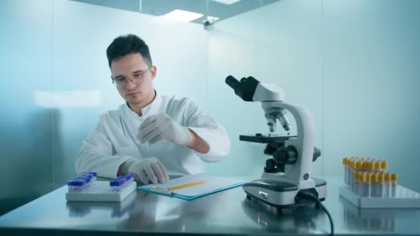 医学研究科学家利用试管和显微镜进行Dna测试实验 并在生物科学实验室写下报告分析 高级化验室穿着白色制服的工程师 — 图库视频影像