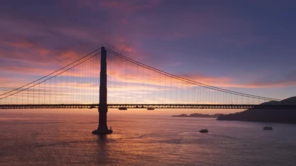 世界著名的金门大桥轮廓 空中悬索桥旧金山地标在电影日落4K美国 背景为粉色紫色云彩的日落天空的壮观全景 — 图库视频影像
