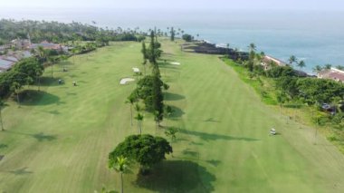 Hawaii sahilinde Pasifik Okyanusu manzaralı lüks bir golf kulübü oteli. Mükemmel yeşil golf sahası ve volkanik sahildeki villalar. Golf sahası tropikal adası. Spor 4K hava arkaplanı