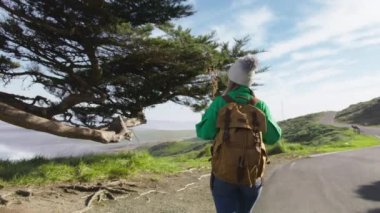 Kırmızı Kamera sırt çantalı turist kadını takip ediyor. Manzaralı yeşil tepeli güzel bir manzara Rey 'lerin okyanus sahilleri güneşli bahar doğa macerası, California. Sinema yavaş çekim ABD turizmi