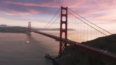 San Francisco 'daki Golden Gate Köprüsü' nde pembe bulutlar ve hareketli arka planda dramatik gül sarısı günbatımı. Ünlü Golden Gate Köprüsü 'nün sinematik hava görüntüsü, San Francisco, Kaliforniya, ABD 