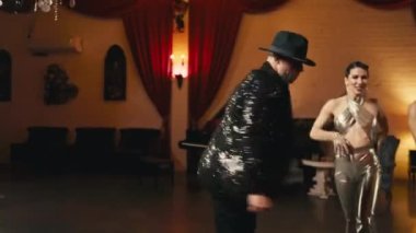 Modern funk caz koreografisinin elementleri genç dansçı çiftler tarafından klas retro stüdyo arka planında sahneleniyor. Erkekler ve kadınlar tutkulu bir şekilde dans ediyor, duygularını yavaş çekimde ifade ediyorlar.