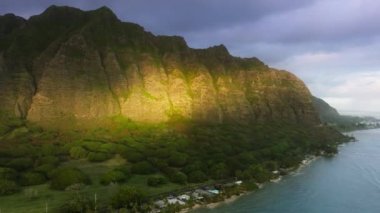 İnsansız hava aracı cenneti Hawaii doğa seyahati. Altın saatinde muhteşem orman dağları olan yeşil tropikal ada. Oahu Adası 'ndaki destansı Kualoa Çiftliği sıradağları manzarasında gün doğumu ışığı parlıyor.