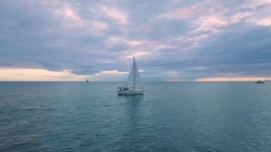 Günbatımından sonra okyanus koyunda sürüklenen yelkenlinin hava görüntüsü. Hawaii, Oahu adasındaki Waikiki sahilinden gemiyle yaz gezisi. Turist yolcularla dolu bir yat. Tekneli sinematik Hawaii sahili suları