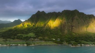 Oahu Adası 'ndaki destansı Kualoa Çiftliği sıradağları manzarasında gün doğumu ışığı parlıyor. İnsansız hava aracı cenneti Hawaii doğa seyahati. Altın saatinde muhteşem orman dağları olan yeşil tropikal ada