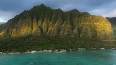 Altın saatinde muhteşem orman dağları olan yeşil tropikal ada. Oahu Adası 'ndaki destansı Kualoa Çiftliği sıradağları manzarasında gün doğumu ışığı parlıyor. İnsansız hava aracı cenneti Hawaii doğa yolculuğu