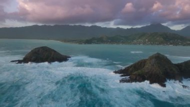 Kailua Oahu Adası, Hawaii Birleşik Devletleri. Pasifik Okyanusu 'ndaki küçük ada silueti. Hawaii tatili. Turizm arka planı 4K destansı gün doğumu. Na Mokulua Adalarına güneş doğarken düşen manzara dalgaları.