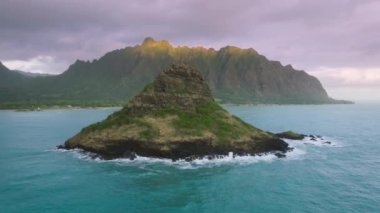 Havai 4K 'nın güzel, sinematik kıyı manzarası. Mokolii Adası 'nın arka planında Kualoa çiftlik manzarası olan havadan görünüşü, Hawaii Oahu adası. Manzaralı yeşil Çinlilerin şapka adasının insansız hava aracı çekimi