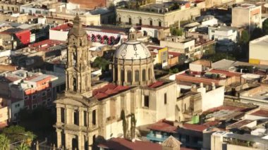 Guadalajara Meksika 'daki San Jose de Gracia kilisesinde uçan insansız hava aracı. Bell Tower ve Beyaz Kubbe 'nin üzerinde güzel altın güneş ışığı parlıyor. Mexico 4K 'daki Latin şehri hakkında sinematik görüşler