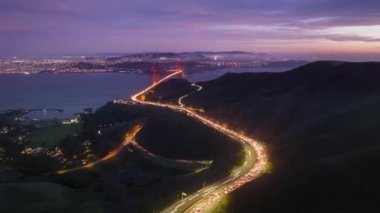 4K insansız hava aracı San Francisco California Skyline 'da hızını kesti. Gece aydınlatmasında Golden Gate Köprüsü 'ne doğru hava trafik akışı hızlanır ve hareketli arka planda günbatımı manzarası vardır. Şehir merkezi manzarası