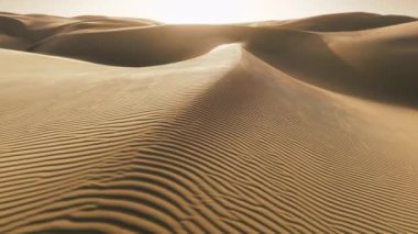 Çöl doğasında, düşük güneş ışığında, kum yüzeyindeki dalgalı dokuyu kapatın. Kum üfleyen güçlü rüzgar inanılmaz bir atış. Gün batımındaki dalgalı kum tepelerinin tepesinde parlak altın kum tabakası.