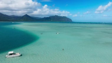 Arka planda sinematik Kualoa Dağları 'nın olduğu Kaneohe sahil barında şnorkelli bir teknenin hava görüntüsü. Hawaii Cennet Adası 'ndaki Oahu sahili. İnanılmaz doğa manzarası mavi göl
