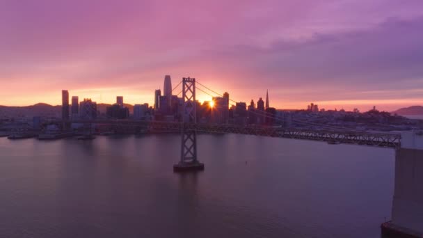 旧金山市五彩缤纷的落日天空 在金融区大楼和湾桥的上空 笼罩着迷人的粉色金色落日云彩 旧金山市市中心 在史诗般的玫瑰紫色落日的天空4K空中 — 图库视频影像