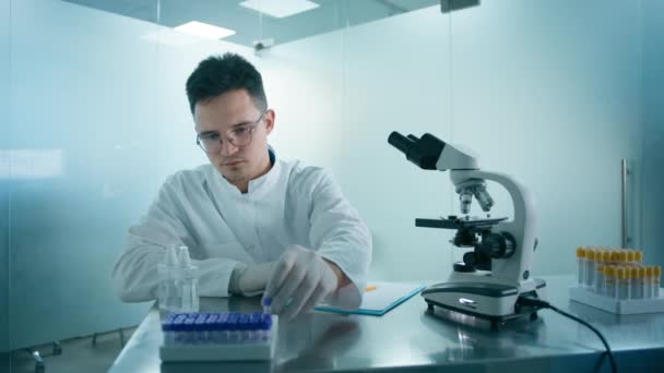 現代の研究室でウイルスサンプルを用いた試験管を見る男性科学者のスローモーション 進歩的な科学技術医学研究室で働く眼鏡と手袋の科学者の男 — ストック動画