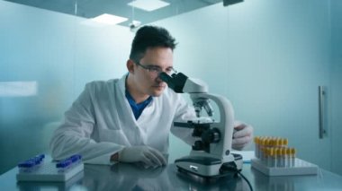 Mikroskop altında bakan yorgun bilim adamının portresi petri kabı örneğini analiz eder. İlaç kullanan büyük bir ilaç laboratuarı. Tıbbi gelişim laboratuvarında çalışan zeki insanlar kavramı