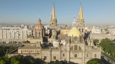 Guadalajara Latin şehrindeki yeşil plaza parkının üzerindeki güzel açık mavi gökyüzü. İHA, Liberacion 4K plazasında yavaş uçuyor. Guadalajara Katedrali 'nin neo gotik manzaralı cephesi, kuleleri ve kubbesi Meksika