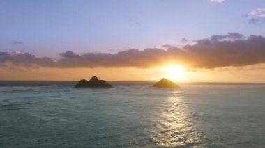 Efsanevi deniz manzarasının üzerinde açık mavi Pasifik Okyanusu 'nda Na Mokulua adalarının siluetleriyle destansı bir gündoğumu. İdillik tatil tatili Hawaii adasında. Amerikan turizm arka planı 4K kopyalama alanı