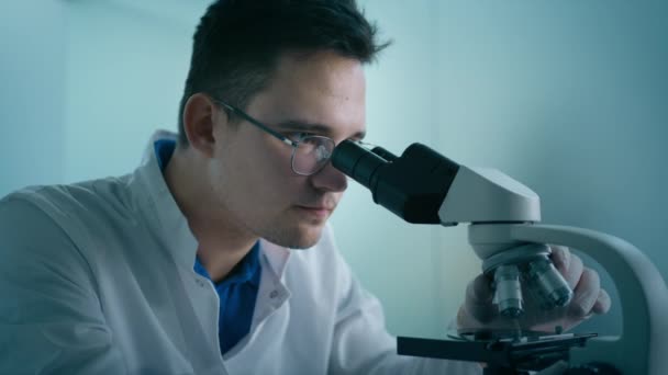 Close Microbioloog Man Wit Medisch Uniform Kijkt Onder Microscoop Analyseren — Stockvideo